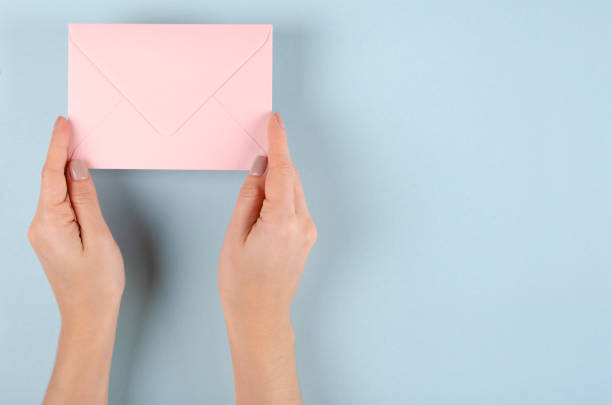 istock Hand with pink paper envelope composition on blue background. 1185650368