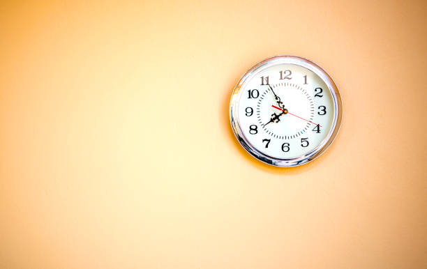 istock The white wall clock hanging on the orange color wall, 1185650820