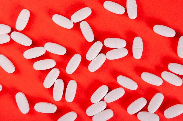 istock White medical pills composition on red background. 1185650876