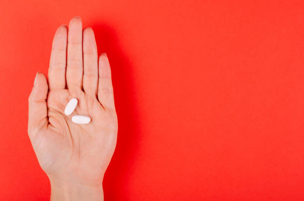 istock Hand with white medical pills composition on red background. 1185650954