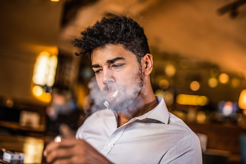Mid adult man smoking a cigarette in the bar.