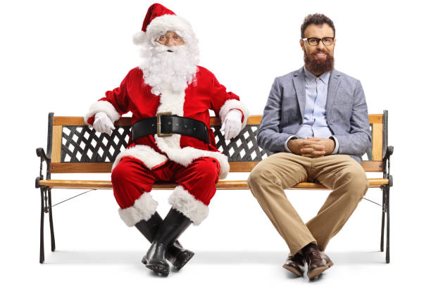 weihnachtsmann und ein jüngerer mann sitzen auf einer bank - full grown stock-fotos und bilder