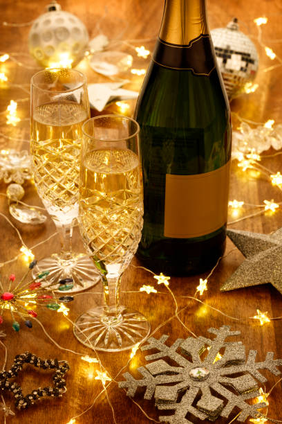 Champagne flutes and bottle with christmas lights, baubles and silver stars decorations Champagne flutes and bottle with christmas lights, baubles and silver stars decorations, on a wooden table hogmanay photos stock pictures, royalty-free photos & images