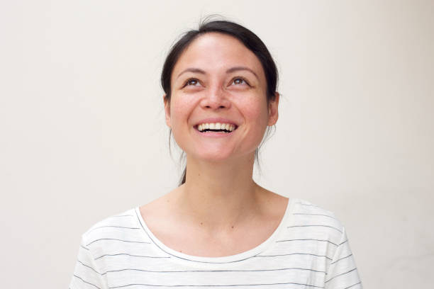 istock happy young woman smiling and looking up by white background 1185657446