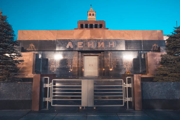 closed turnstile at lenin's mausoleum entrance at red square in moscow. granite building where tomb of russian leader is held shot at blue sky background. engraved text "lenin" in russian language. - vladimir lenin imagens e fotografias de stock