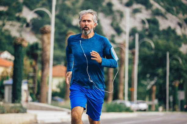 hombre mayor activo corriendo en un día soleado - men gray hair vitality healthy lifestyle fotografías e imágenes de stock
