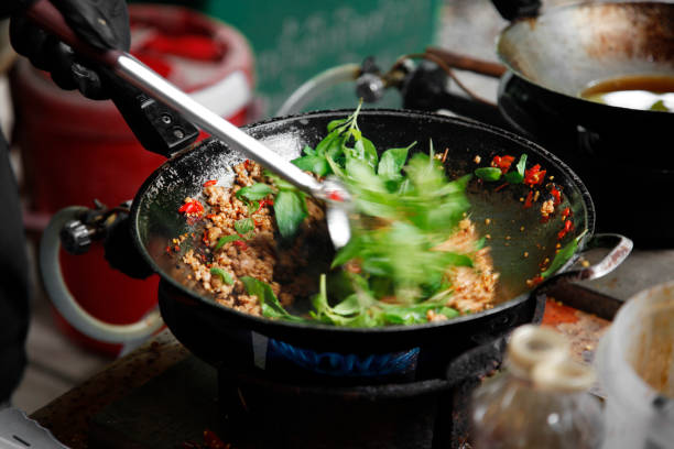 cooking Thai stir-fried minced pork with basil in the metal pan with stir fry spatula stock photo