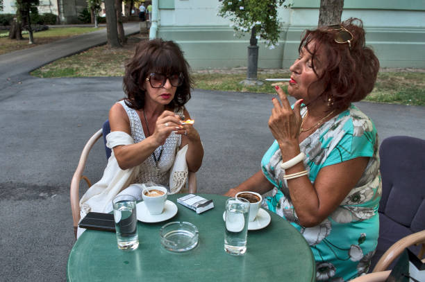 Meeting at a summer garden restaurant with two women over coffee and cigarettes. They haven't seen each other in a long time.