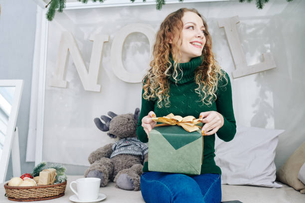istock Cheerful woman in sweater opening present 1185663178
