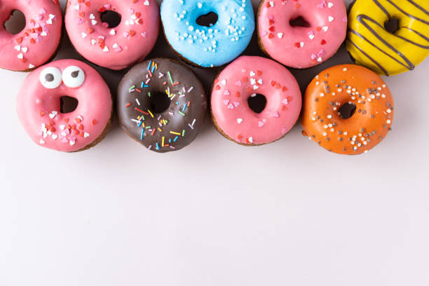 istock Different donuts with icing on pastel pink background. Sweet donuts, top view, flat lay. 1185665698