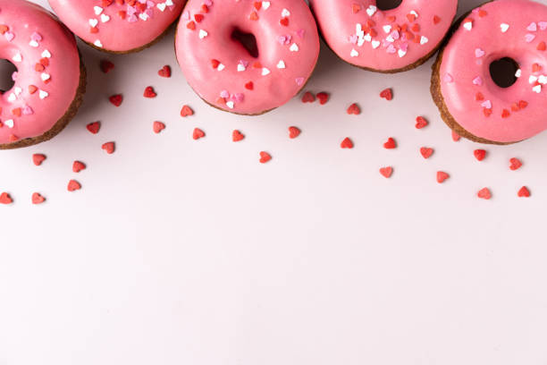 Donut with heart shaped decor on pink background. Top view with copy space