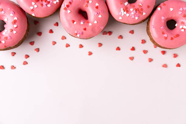 Donut with heart shaped decor on pink background. Top view with copy space Donut with heart shaped decor on pink background. Top view with copy space heart shape valentines day chocolate candy food stock pictures, royalty-free photos & images