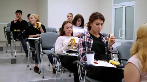 Students eat bananas and sandwiches in classroom.