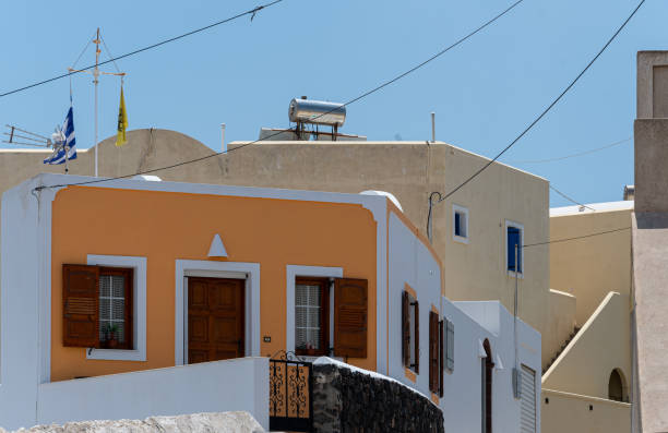 Santorini, Oia, morning dawn in the romantic streets of the fishing village, White and colorful houses built on a cliff above the Caldera, a narrow cobbled street and a beautiful blue sky.