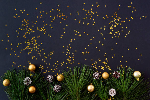 istock Flat lay christmas border with pine branches and golden confetti on a dark background 1185669502