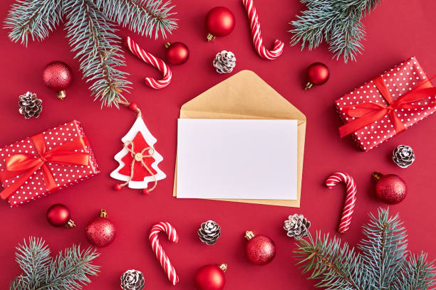 istock Mockup white greeting card and envelope with red christmas balls, spruce branches and gift box on a red background 1185669530