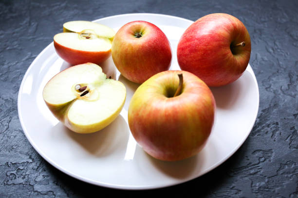 istock Apples lying on the white plate. Still life photo. Black background. 1185671072