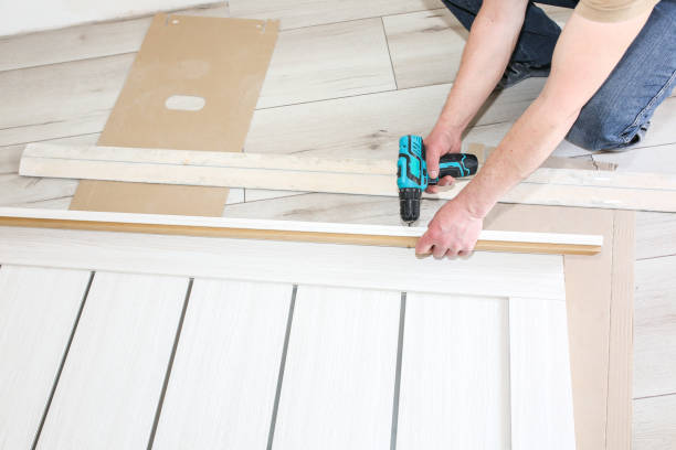 istock Man is installing the doors. Carpenter is making holes with the drill in hinges. Repair works. Maintenance in the apartment. 1185671509