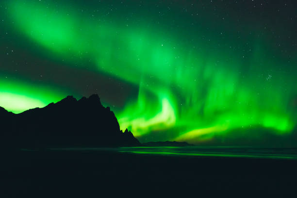 Northern Lights dancing in Iceland View of beautiful bright Aurora borealis with green, yellow and purple colors at the Stokksnes beach with Mountain View in East iceland iceberg dramatic sky wintry landscape mountain stock pictures, royalty-free photos & images