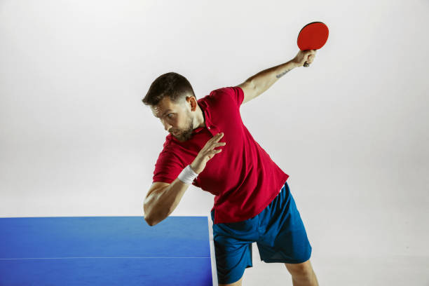 istock Young man playing table tennis on white studio background 1185673010