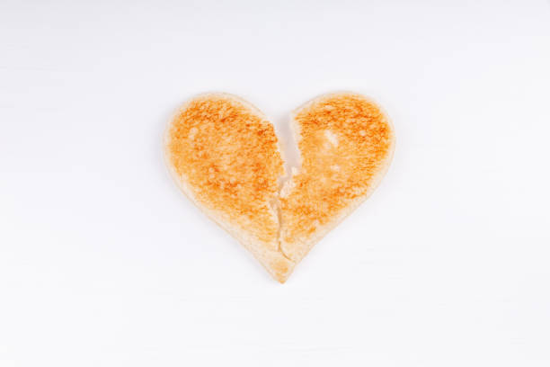 Bread toast broken heart symbol on white background. The concept of divorce, breakup, unhappy relationship.