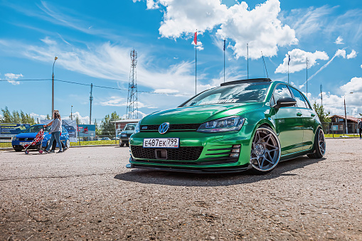 Moscow, Russia - July 06, 2019: German Lowrider in the parking lot in open space. Tuned Volkswagen Golf 7 tightened into a green vinyl film. Installed exclusive wheels, air suspension. Demonstration of working air suspension