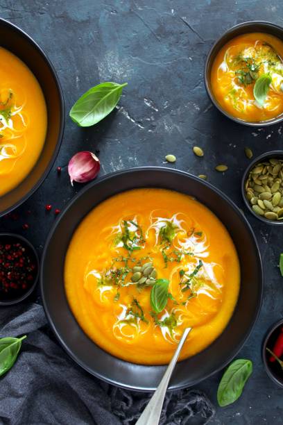 istock Pumpkin and carrots soup with cream and basil on dark background. 1185676284