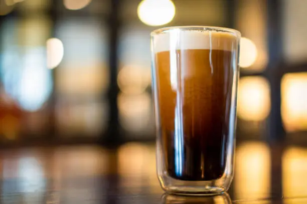 Beautiful texture and layers of Nitro Cold Coffee served in a double wall glass close up.