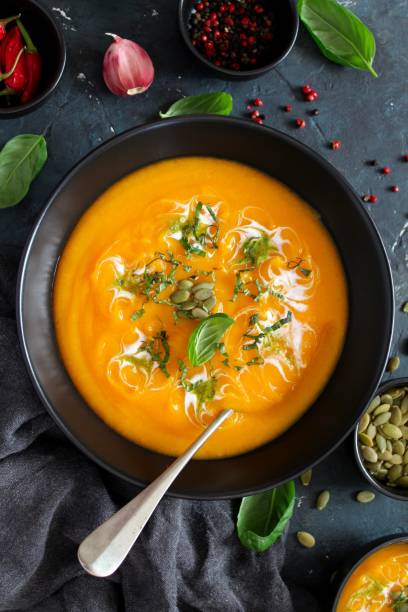 istock Pumpkin and carrots soup with cream and basil on dark background. 1185676879