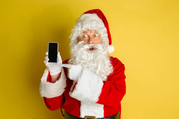 istock Santa Claus with modern gadgets isolated on yellow studio background 1185676888
