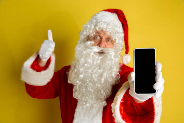 istock Santa Claus with modern gadgets isolated on yellow studio background 1185676894