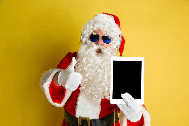 istock Santa Claus with modern gadgets isolated on yellow studio background 1185676923