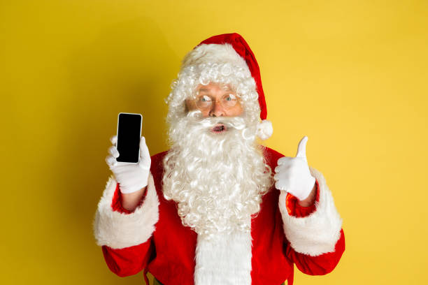 istock Santa Claus with modern gadgets isolated on yellow studio background 1185676924