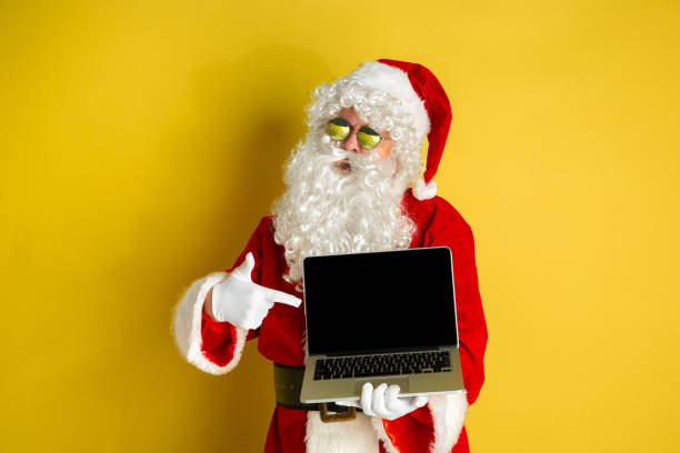 istock Santa Claus with modern gadgets isolated on yellow studio background 1185676928