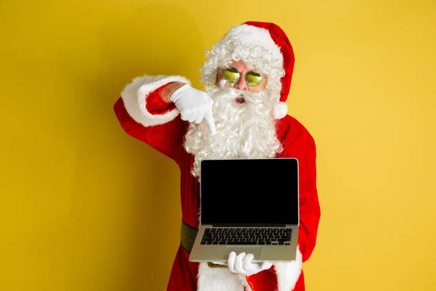 istock Santa Claus with modern gadgets isolated on yellow studio background 1185676936