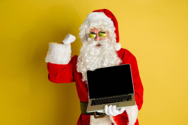 istock Santa Claus with modern gadgets isolated on yellow studio background 1185676942