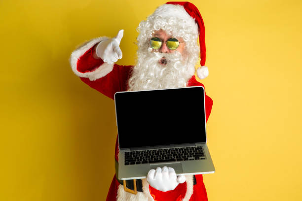 istock Santa Claus with modern gadgets isolated on yellow studio background 1185676948