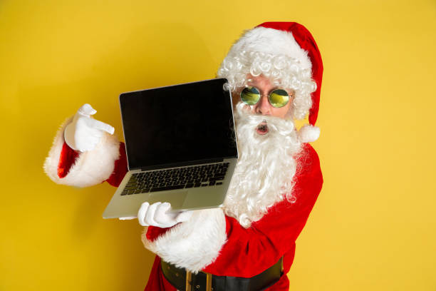 istock Santa Claus with modern gadgets isolated on yellow studio background 1185676954