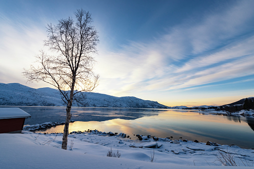 Sunset over a winter landscape at the Straumsbotn Fjord in Northern Norway during a beautiful winter day.