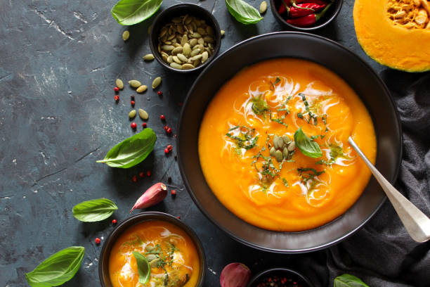 istock Pumpkin and carrots soup with cream and basil on dark background. 1185678334
