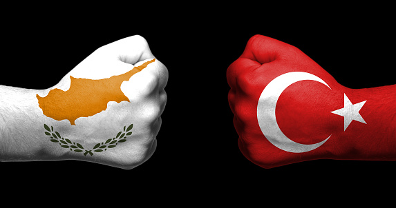 Banderas de Turquía y Chipre pintadas en dos puños apretados uno frente al otro sobre fondo negro / relación tensada entre Turquía y Chipre concepto photo