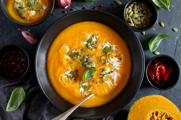 istock Pumpkin and carrots soup with cream and basil on dark background. 1185678450