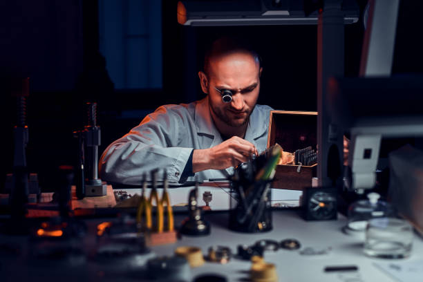 istock Focused man is working at his workshop with monocle and other tools repairing old watches 1185678509