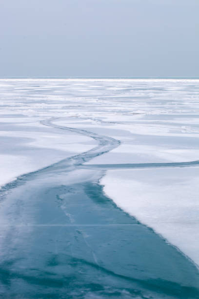 istock Frozen lake surface covered in snow with a frozen ice path 1185679592