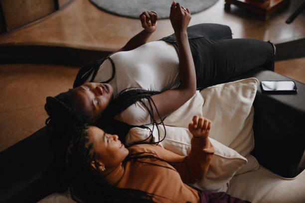 istock Female roommates laying on the sofa and talking and dancing 1185681334