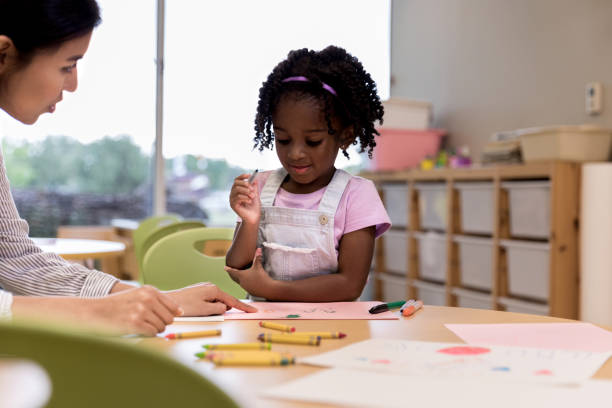 istock Art teacher helps cute student with drawing 1185682022