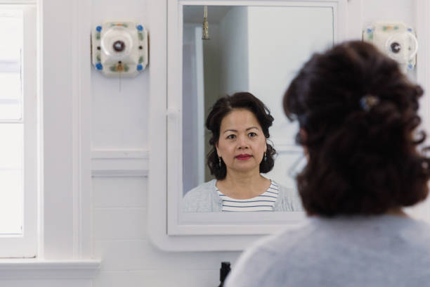 istock With serious look, senior widow looks at reflection in mirror 1185682154