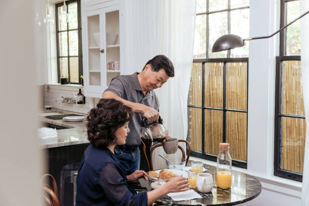 istock Senior husband stands to pour coffee while wife eats 1185682210