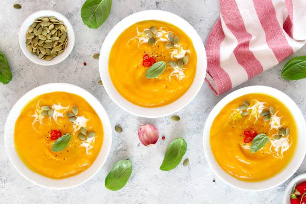 istock Pumpkin and carrots soup with cream and basil on light background. 1185682774