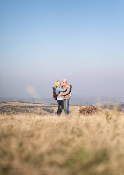 pareja de la tercera edad abrazando en un campo salvaje i naturaleza. - face to face twilight togetherness vertical fotografías e imágenes de stock